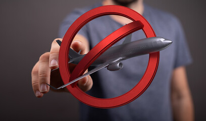 Image depicts a hand holding a model airplane crossed out by a red circle, symbolizing travel bans...