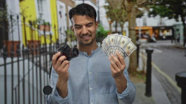 Young man holding camera and dollar bills smiling on city street, capturing a vibrant outdoor cityscape with trees and buildings in the background, showcasing success and hobbies.