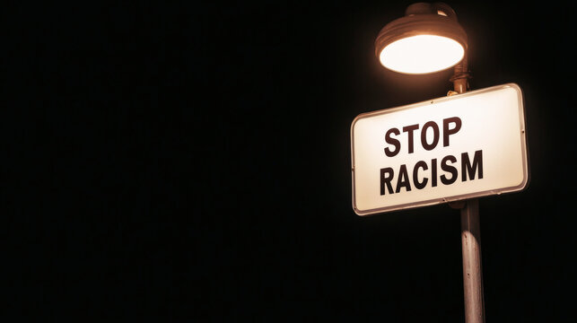Illuminated white lightbox displays powerful message urging to stop racism against a dark backdrop