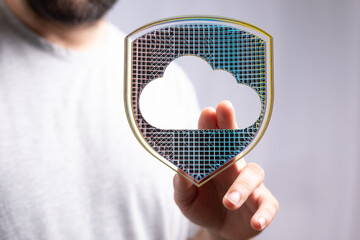 Image of a person interacting with a digital shield protecting cloud data.  Illustrates...
