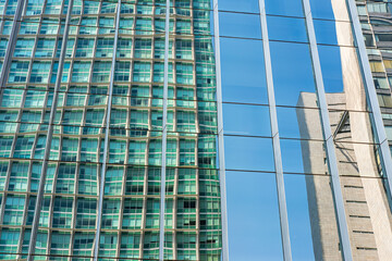Reflections of blue and green ripple across a modern skyscraper facade, forming fragmented urban surfaces and capturing geometric energy and bold contrasts in a vibrant contemporary cityscape.
