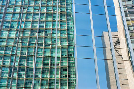 Reflections of blue and green ripple across a modern skyscraper facade, forming fragmented urban surfaces and capturing geometric energy and bold contrasts in a vibrant contemporary cityscape.