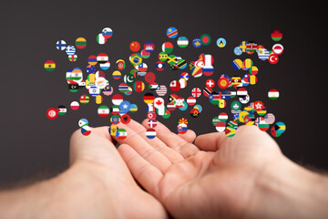 Image of hands holding many flags, representing global unity and connection.