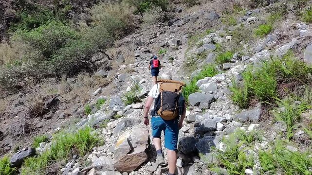 Two Caucasian hikers traversing rugged terrain high above Tiger Leaping Gorge in Yunnan, China