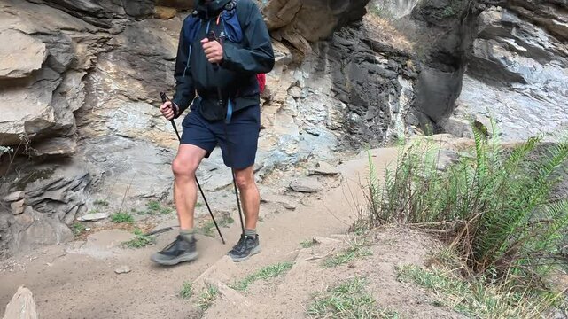 Two Caucasian hikers carefully following a narrow cliffside path at Tiger Leaping Gorge in Yunnan