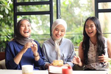 Three Asian Female Friends Happy Sitting in Cafe Next to Window, Smiling after Doing Tiktok Challenge