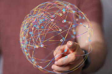 Abstract image of a hand interacting with a colorful, interconnected global network sphere. ...