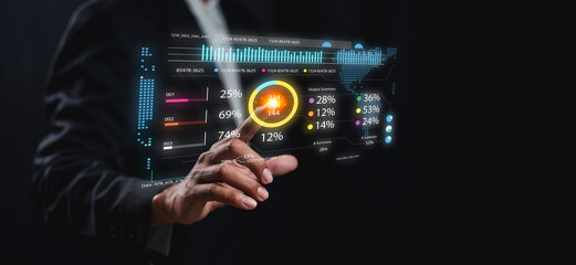 A person interacts with a futuristic transparent touchscreen displaying various colorful data charts and statistics in a dark setting.