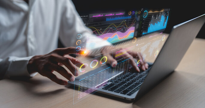 Person interacting with a laptop displaying futuristic transparent data charts and graphs, illustrating advanced data analytics and technology use.