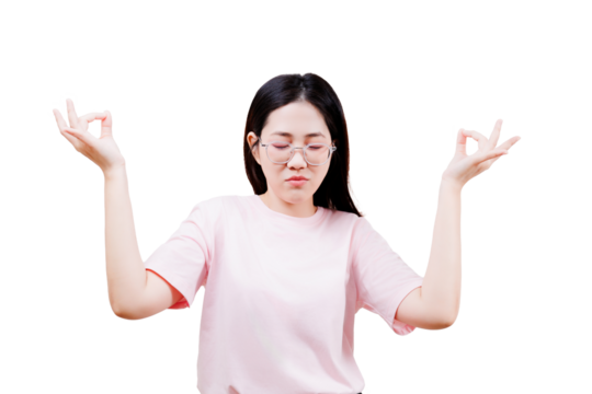 A young woman with glasses and a pink shirt is meditating with her eyes closed and hands in a mudra pose.