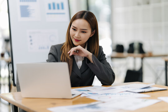 Strategic Insights: A focused professional at a wooden desk, engrossed in the data presented by a laptop, embodying the essence of office analytical activities, data research, and digital connection. - Powered by Adobe