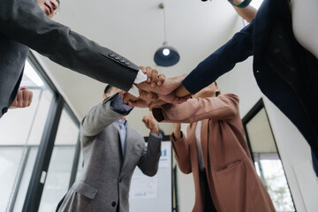United Hands: A group of diverse professional joins hand, symbolizing unity, collaboration, and shared success in a modern workplace setting.