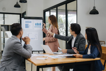 Business Collaboration: A team of professionals intently examines data on a flip chart during a business presentation, a collaborative effort.