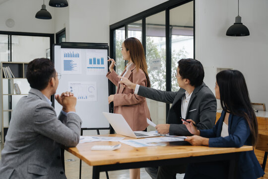 Business Collaboration: A team of professionals intently examines data on a flip chart during a business presentation, a collaborative effort.