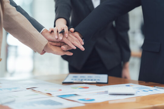 Teamwork Handstack: A close-up captures a group of business professional, their hands intertwined in a strong display of collaboration and unity over the documents.
