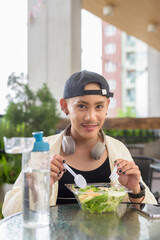 Young non binary gay man eating salad