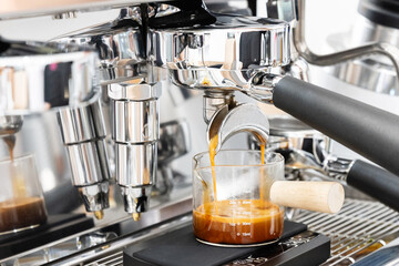 Coffee machine brewing espresso in to glass cup.Barista while preparing and working with coffee...