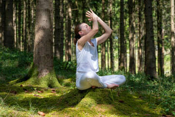 woman sitting cross-legged and meditating in a peaceful forest setting