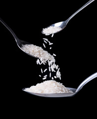 spoon with falling white rice grains on black background