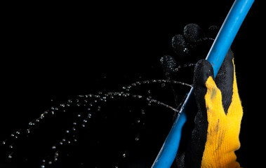 Water leaking on rubber water hose on dark background