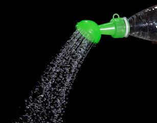Water pouring from watering can spout on black background