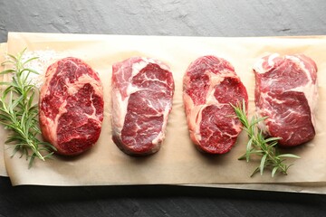 Pieces of raw beef meat and spices on black table, top view