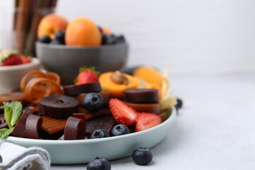 Tasty candied leather rolls, fruits and berries on white table, closeup. Space for text