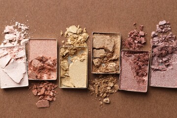 Beautiful eyeshadow refill pans on brown background, flat lay