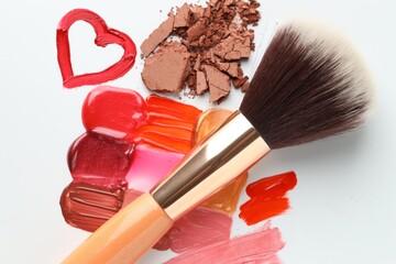 Different cosmetic products and makeup brush on white background, flat lay