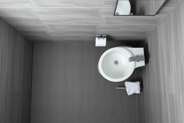 Topdown shot of a modern bathroom featuring a white sink gray tiles and a small mirror