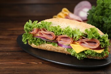 Tasty baguette sandwich with ham, cheese and vegetables on wooden table, closeup