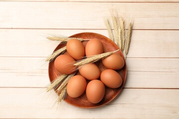 Fresh eggs and spikes on light wooden table, flat lay