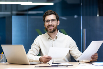 Photo of a smiling young man, company manager and CEO, sitting confidently in front of the camera...