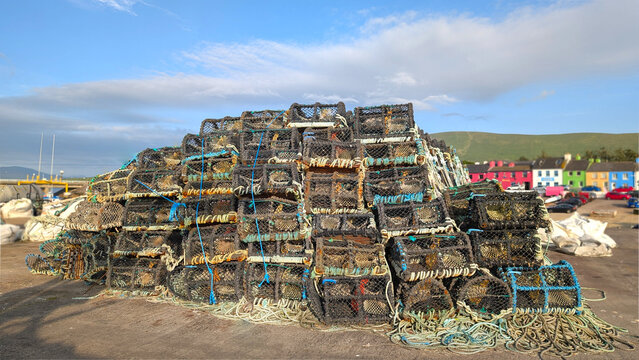 A stack of Lobster traps arranged neatly on a coastal dock in a rural fishing village Portmagee in Ireland. Traditional fishing industry concept. Golden hour lighting