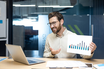 A young man, a company director and specialist, holds an online meeting with partners and clients,...