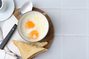 Traditional asian breakfast with half-boiled eggs in bowl, coffee and toasted bread on white tiled table, flat lay. Space for text