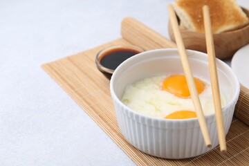 Traditional asian breakfast with half-boiled eggs in bowl, soy sauce, chopsticks and toasted bread...