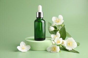 Cosmetic product and jasmine flowers on green background