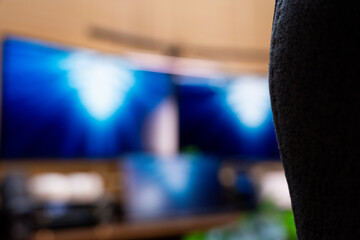 A detailed view of a modern and organized workspace, showcasing dual monitors displaying dynamic blue visuals, complemented by indoor plants and a collection of mechanical keyboards.