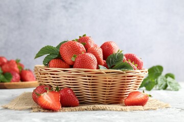Delicious ripe strawberries and green leaves on grey table, closeup