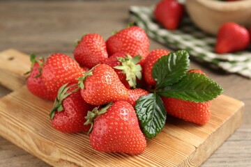 Delicious ripe strawberries and green leaves on table, closeup