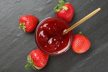 Tasty homemade strawberry jam and berries on black table, top view