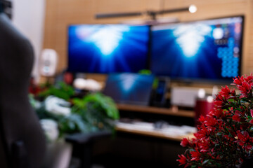 A detailed view of a modern and organized workspace, showcasing dual monitors displaying dynamic blue visuals, complemented by indoor plants and a collection of mechanical keyboards.