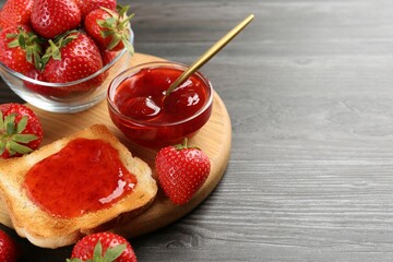 Toast with tasty homemade strawberry jam and berries on wooden table, closeup. Space for text