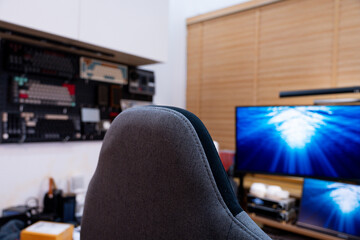 A detailed view of a modern and organized workspace, showcasing dual monitors displaying dynamic blue visuals, complemented by indoor plants and a collection of mechanical keyboards.