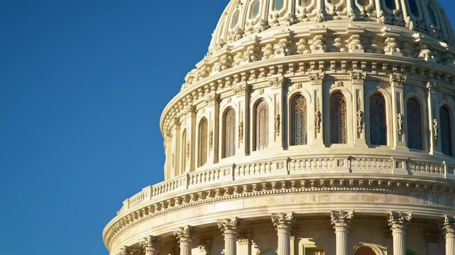 The US Capitol domes upper portion shows architectural details against a clear blue sky
