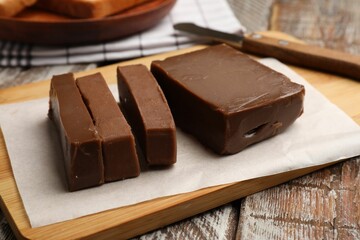 Pieces of tasty chocolate butter and knife on wooden table, closeup