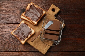 Tasty chocolate butter, slices of bread and knife on wooden table, top view