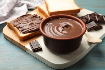 Tasty chocolate butter and pieces on light blue wooden table, closeup