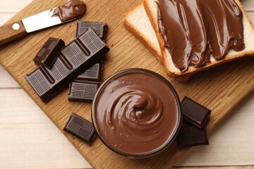 Tasty chocolate butter, pieces and sandwiches on wooden table, top view